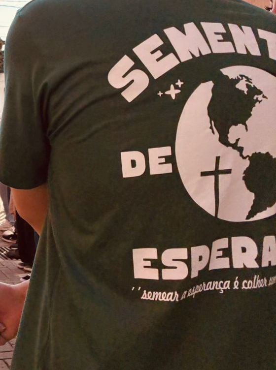 Dois jovens de mãos dadas, com a camiseta verde dos Sementes de Esperança